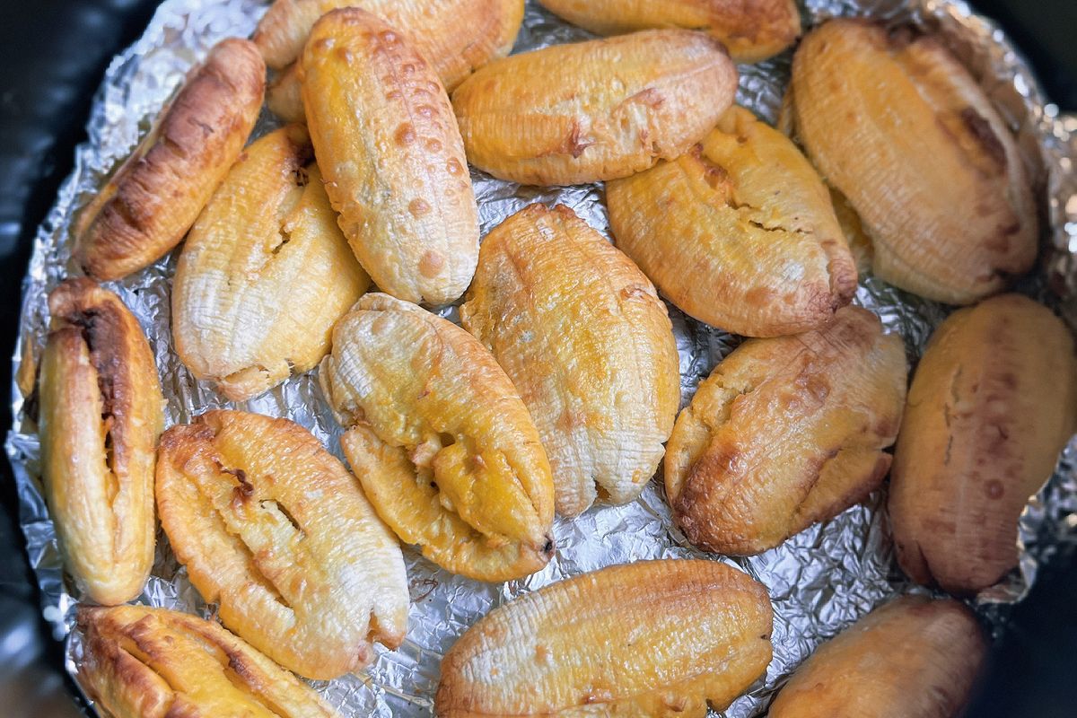 Golden baked plantains in a single layer on foil inside an air fryer