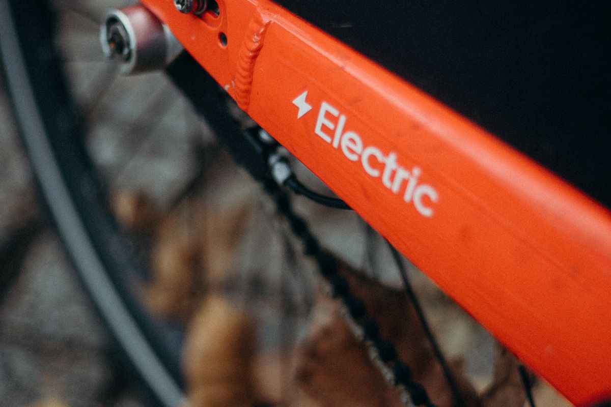 Close-up of an orange electric bicycle frame and chain