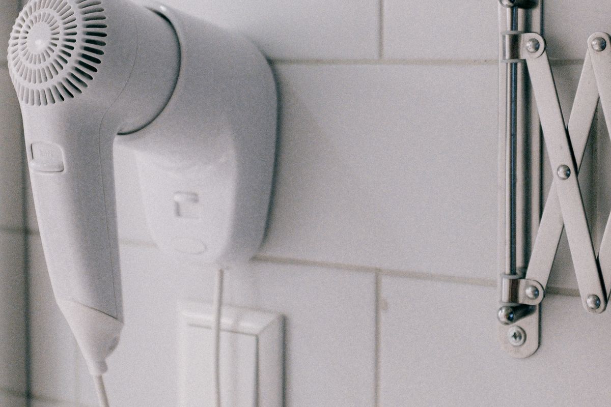 A white wall-mounted hair dryer in a tiled bathroom